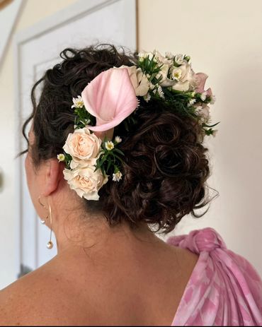 Romantic accentuated natural curly bridal updo with pink flowers by NYC hairstylist, Beauty by Denoi