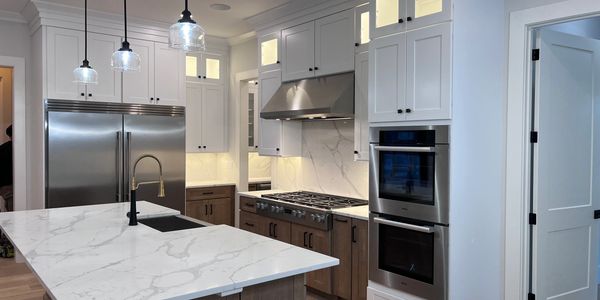 Modern kitchen with marble countertops, stainless steel appliances, and white cabinetry.