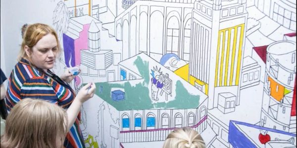 Woman teaching children with a cityscape drawing.