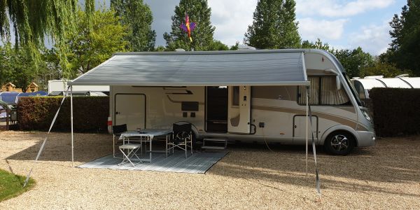 A motorhome with an extended awning and outdoor seating area.