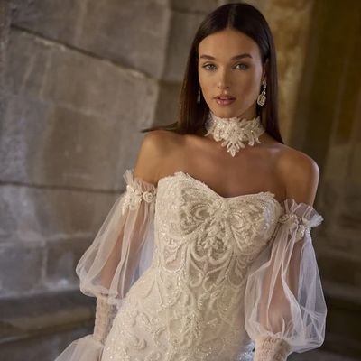 Woman in an elegant white lace wedding dress with sheer sleeves.