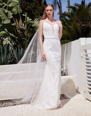Bride in elegant white wedding gown with veil outdoors.