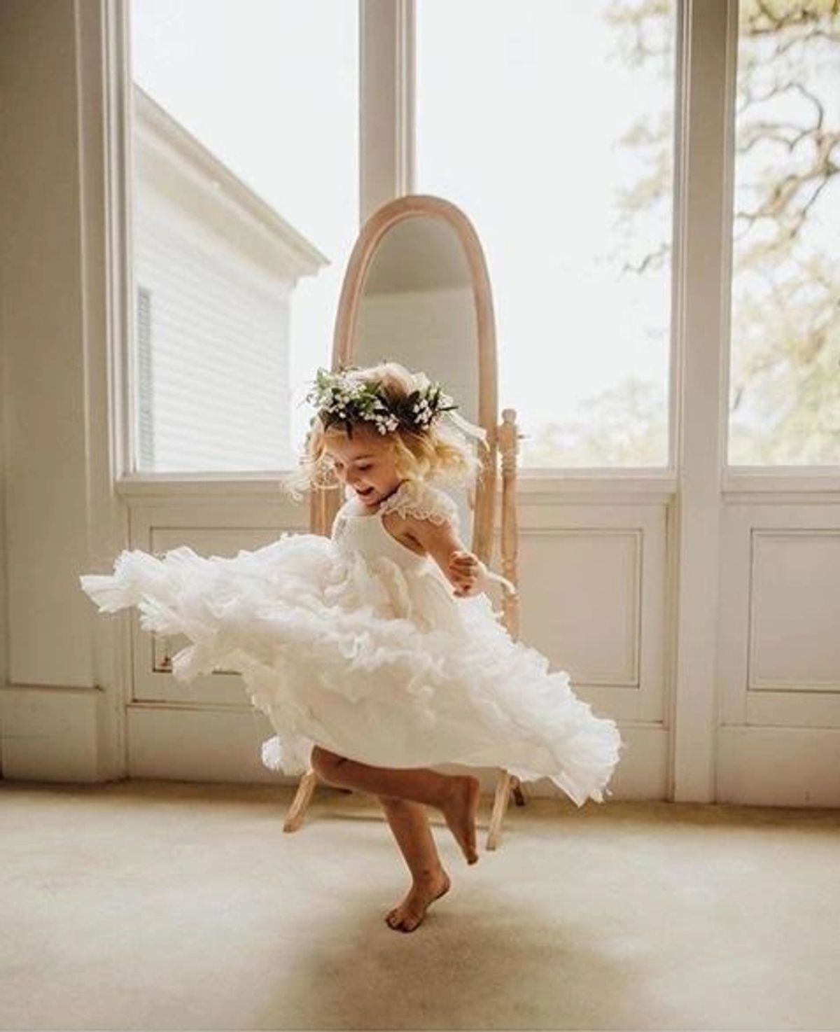 Little girl twirling in a white flower girl dress with a flower crown
