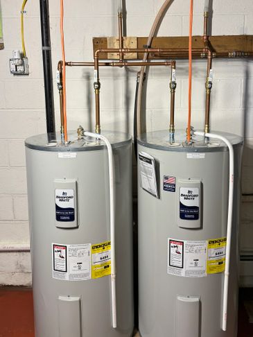 Two Bradford White water heaters installed side by side in a basement.