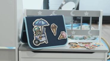 Children's book and paper cutouts on a chair.