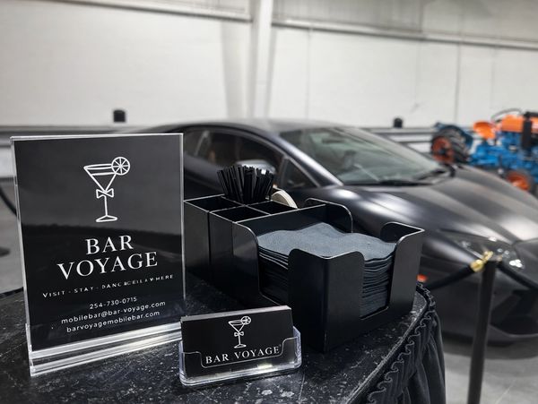 Bar Voyage promotion setup with a luxury car in the background.