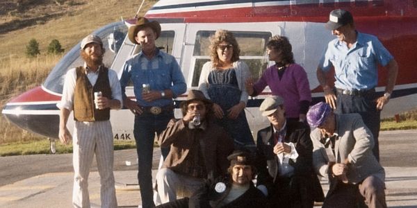 Group of people posing in front of a helicopter.