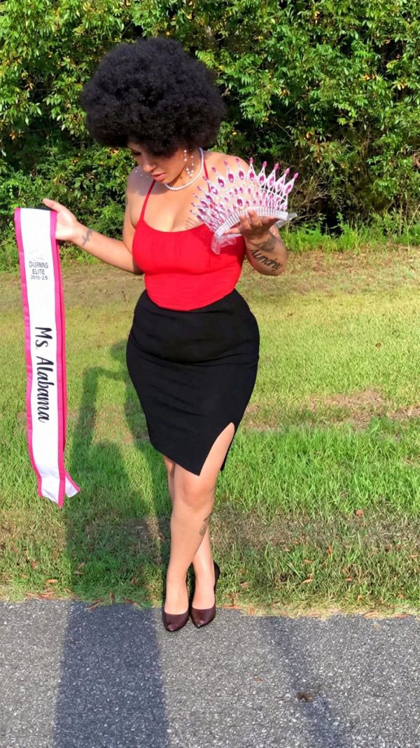 Woman holding Ms Alabama sash and crown outdoors.