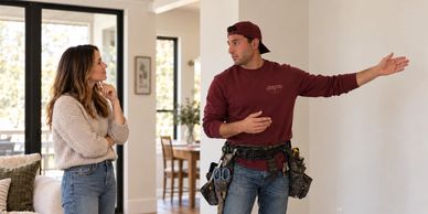 Technician explaining a repair to a woman at home.