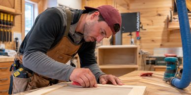 Man sanding a wooden frame in a workshop.