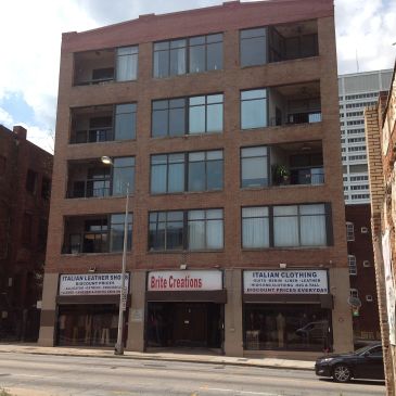 Four-story brick commercial building with clothing shops.