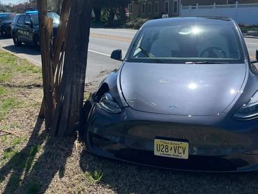 A Tesla car crashed into a wooden utility pole by the roadside.