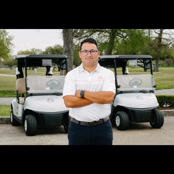 Man standing confidently between two golf carts.
