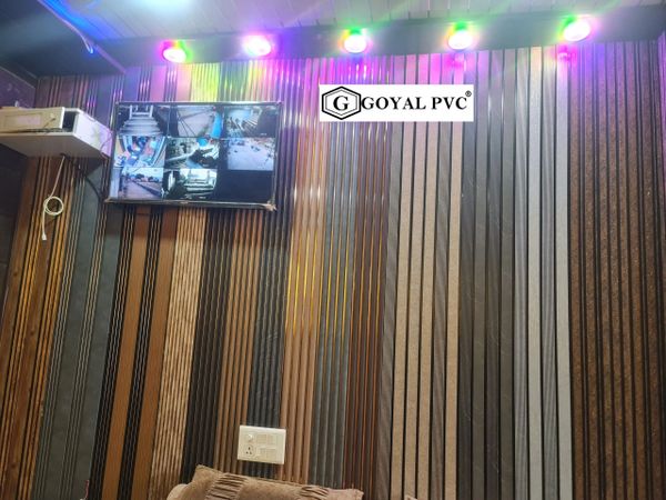 Interior wall with vertical striped panels and CCTV monitor under colorful ceiling lights.