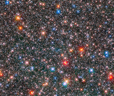 A dense star field with colorful stars shining in space.