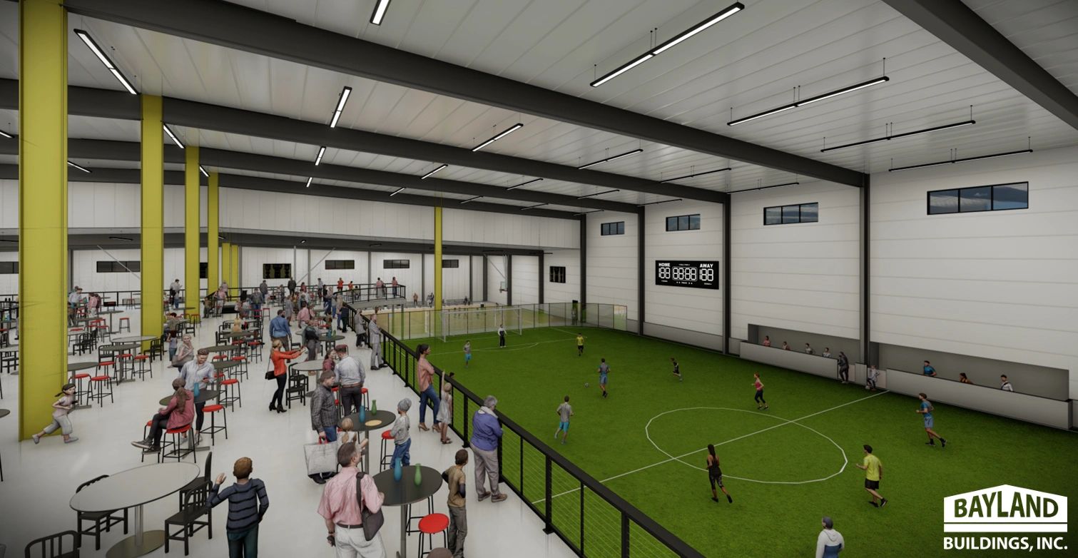 Indoor soccer game with spectators on a balcony.