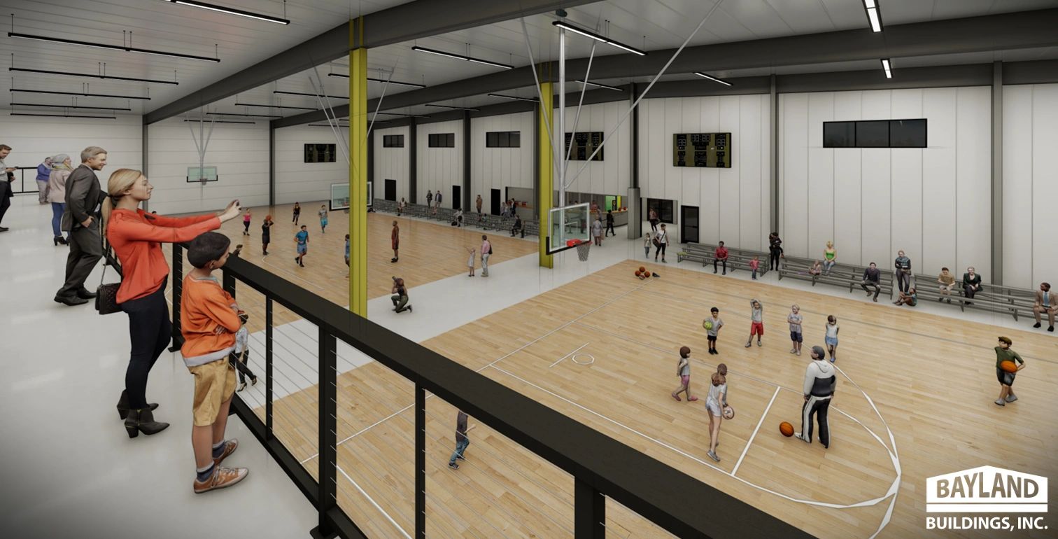 Inside view of a gymnasium with kids playing basketball and people watching from a balcony.