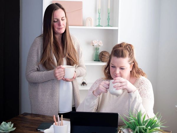 Shellie Munro & Jessica Armstrong drinking coffee and working collaboratively in office