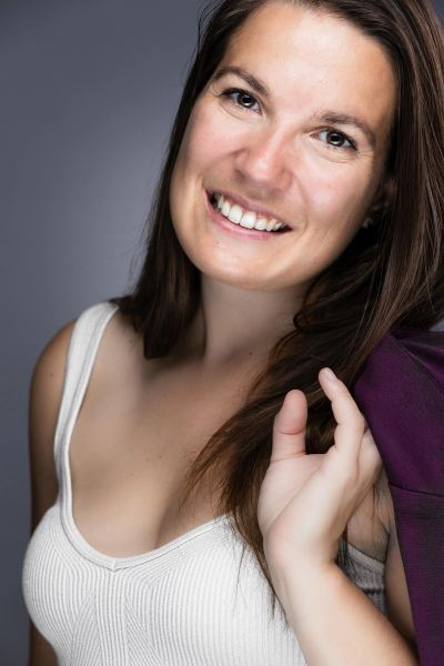 Femme souriante avec veste mauve sur l'épaule.