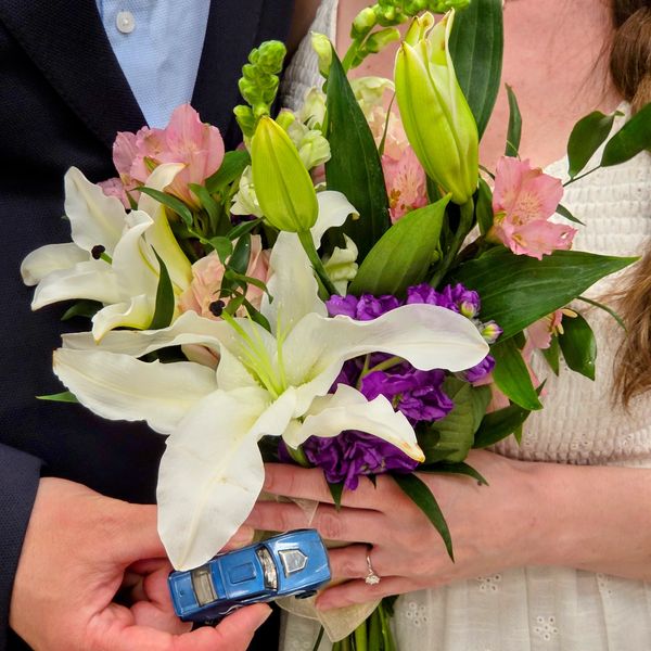Couple holding flowers and toy car.