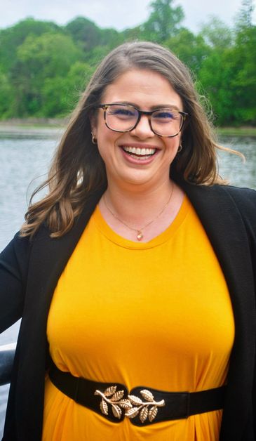 Smiling woman in yellow dress outdoors near water.
