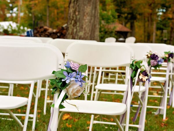 White chairs decorated with flowers for an outdoor event.