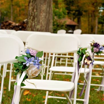 White chairs decorated with flowers for an outdoor event.