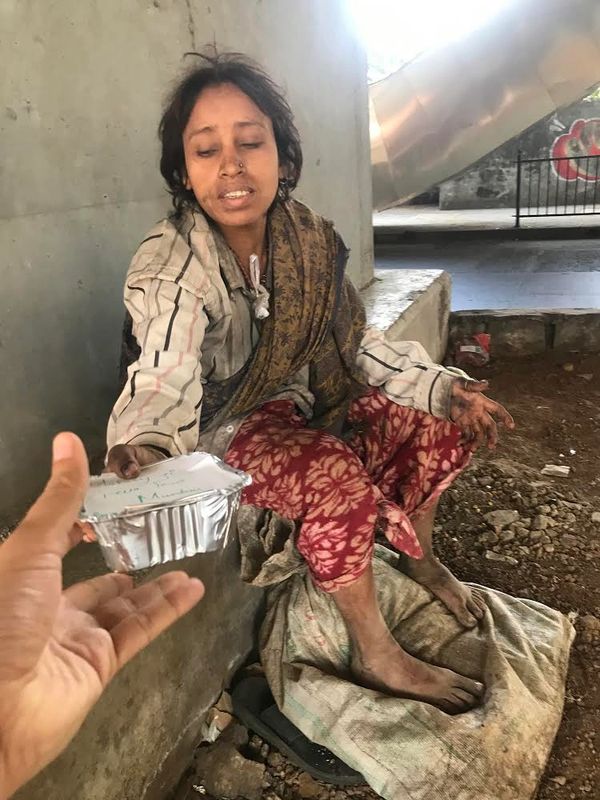 A road sleeper woman taking food from Maharaj ji sewa trust’s team member. 