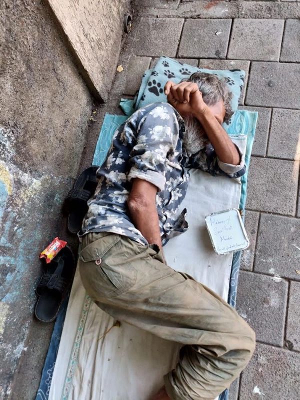 A man is sleeping road side, a food packet kept beside him.