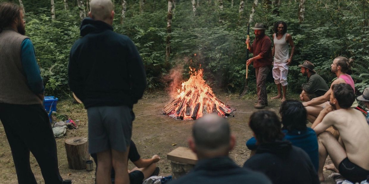 Group gathered around a campfire in a forest setting.