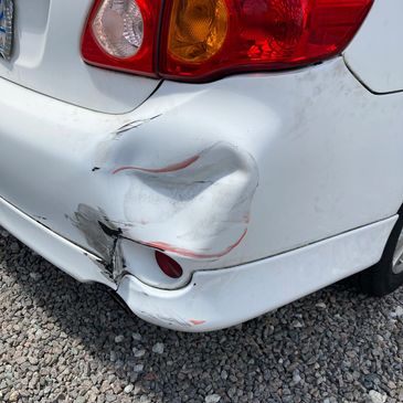 White Toyota corolla with damage to the rear bumper getting an estimate for paintless dent repair.