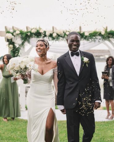 Joyful bride and groom walking after wedding ceremony with confetti.
