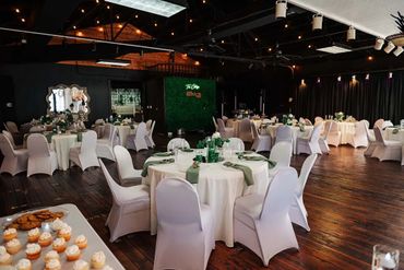 Elegant banquet hall with round tables and white chair covers.