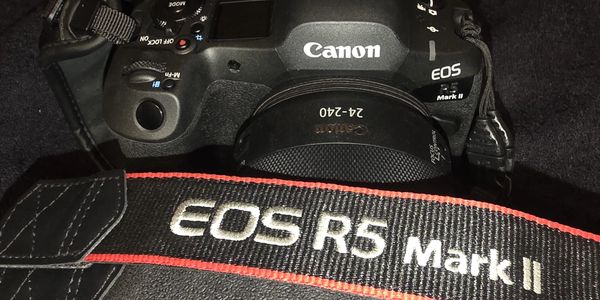 Canon EOS R5 Mark II camera with a 24-240mm lens and matching strap.