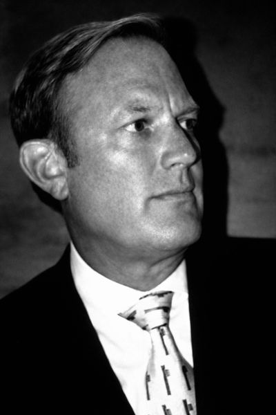 Black and white portrait of a man in a suit and patterned tie.
