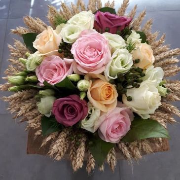 A colorful bouquet of roses surrounded by wheat stalks.