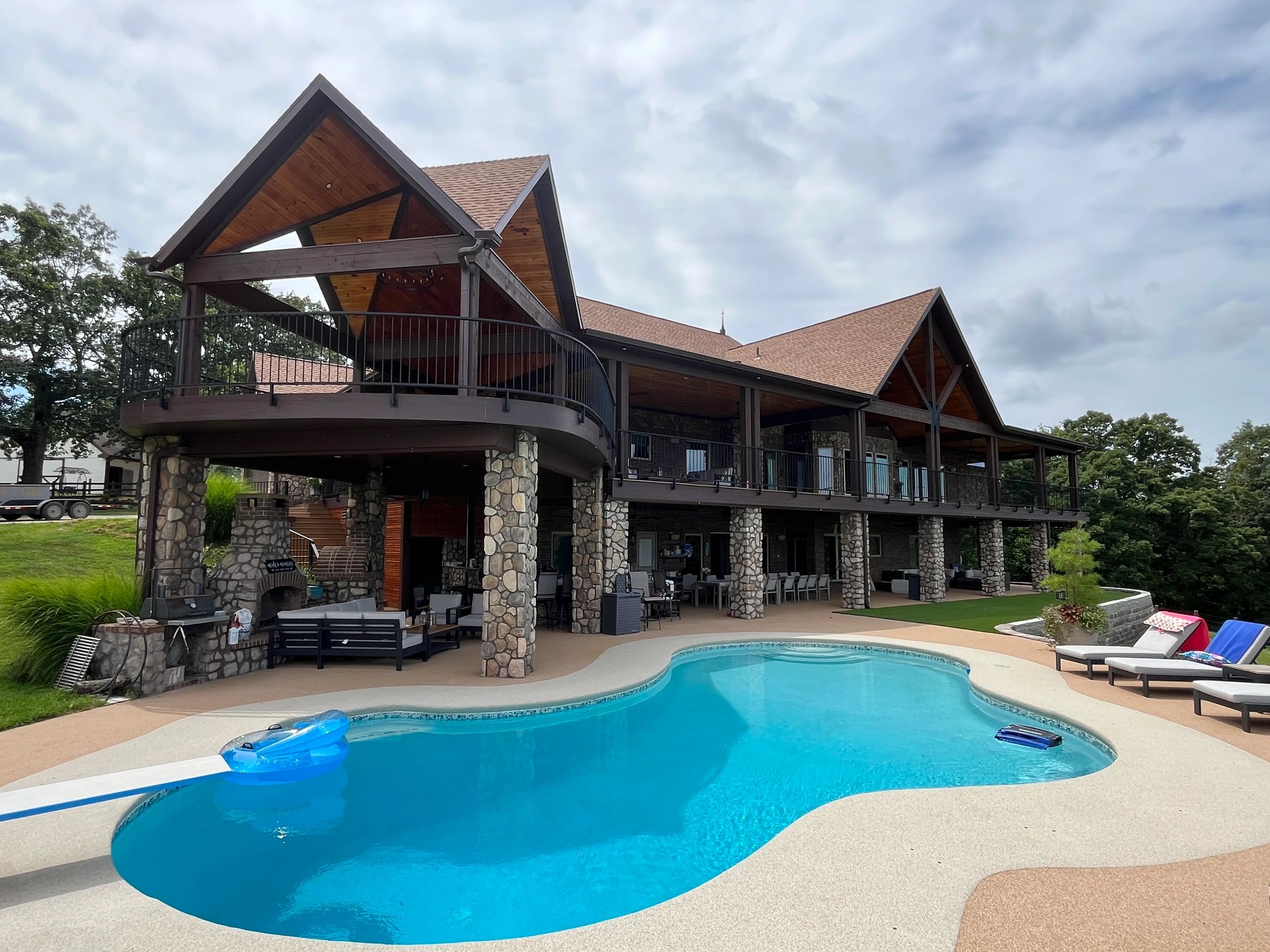 Large stone house with a swimming pool and outdoor lounge area. custom radius metal handrail with stairs and platform