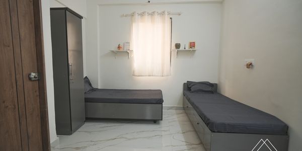 Minimalist twin bedroom with gray beds and white marble flooring.