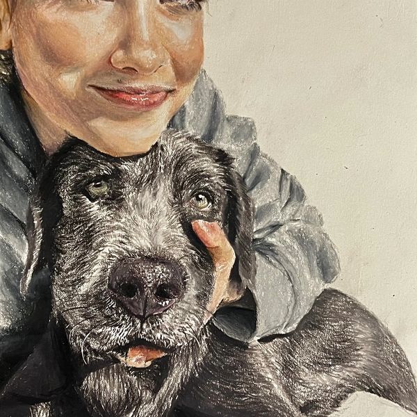 A person affectionately holding a black dog close to their face.