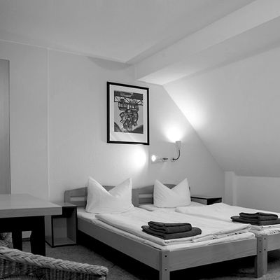 Black and white photo of a tidy bedroom with two beds and folded towels.