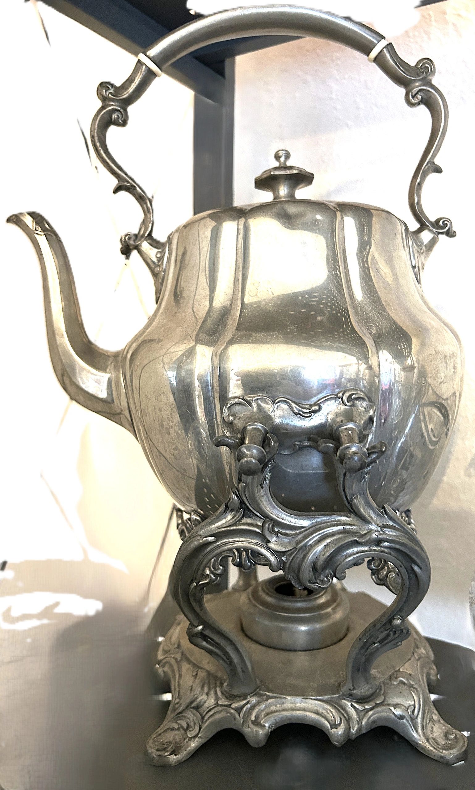Ornate silver teapot with intricate handle and base design.