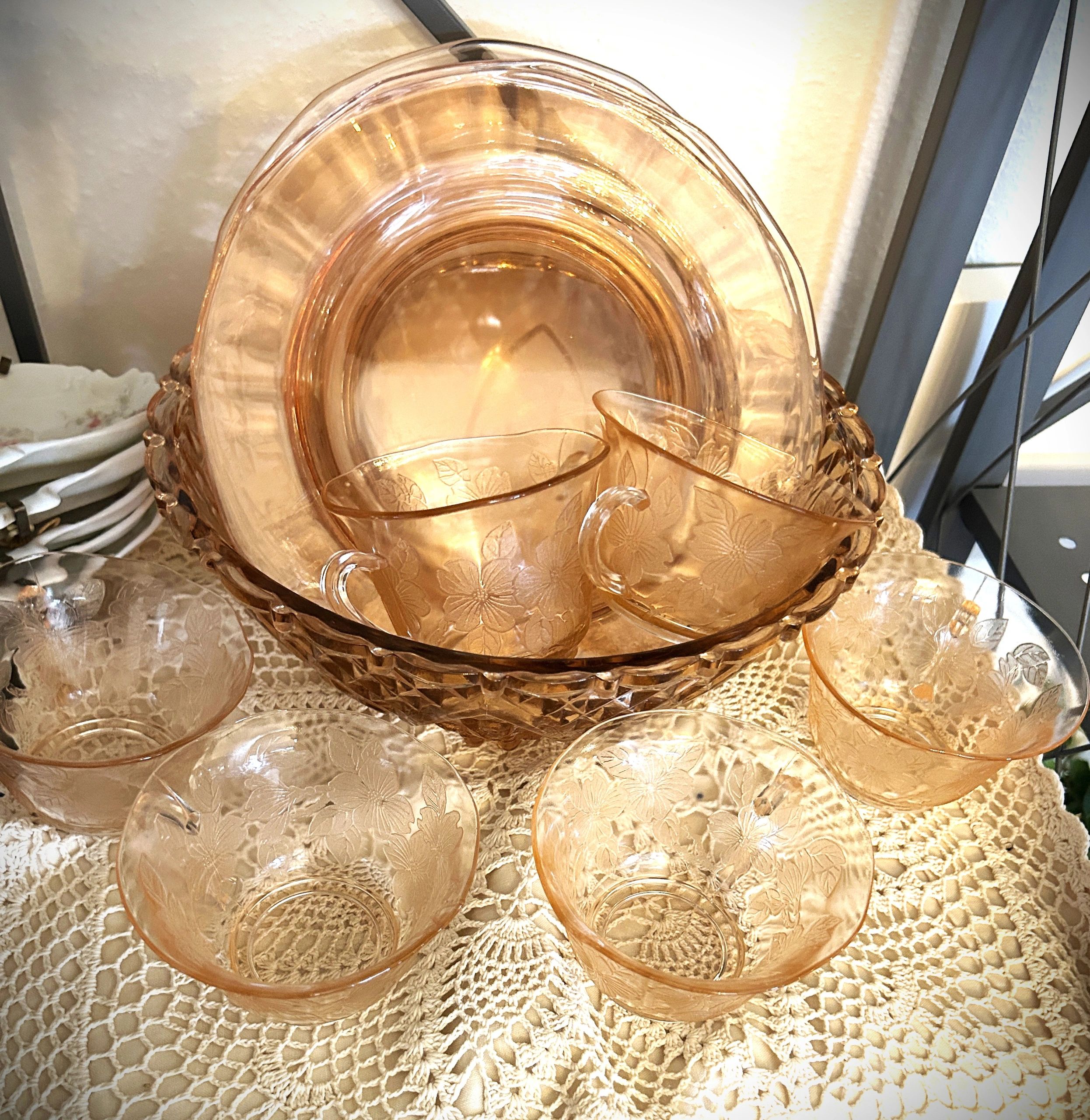 Vintage pink depression glass punch bowl set on a crocheted tablecloth.