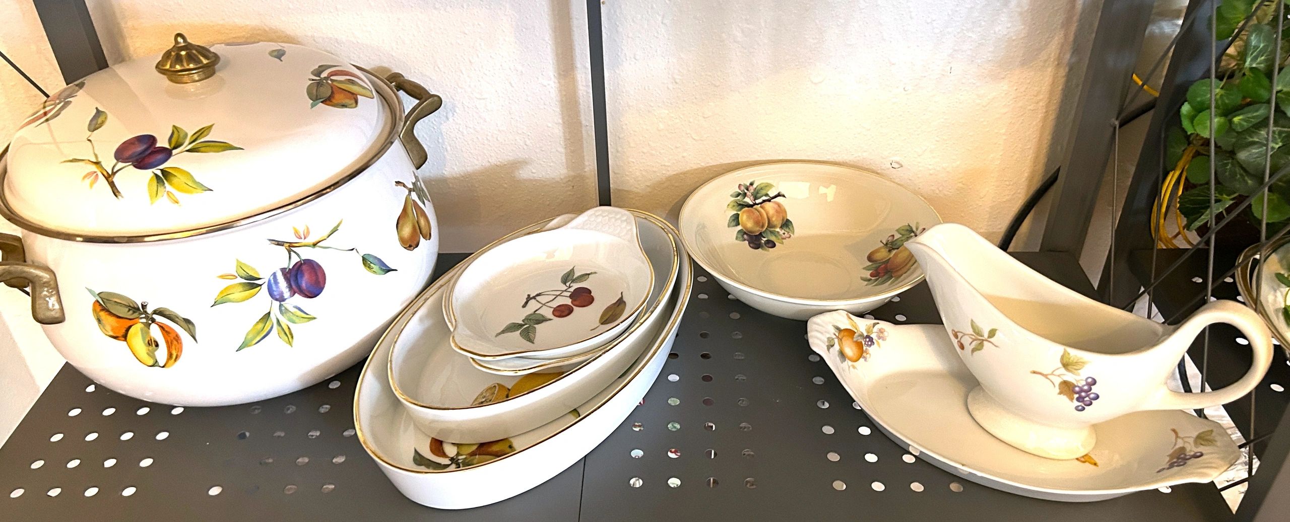 Vintage ceramic kitchenware with fruit designs on a metal shelf.