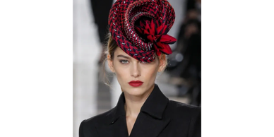 Model wearing a stylish red and black hat with a black outfit.