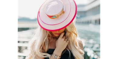 Woman with long blonde hair wearing a large sunhat.