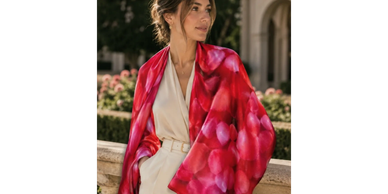 Woman in a beige outfit with a vibrant pink shawl.