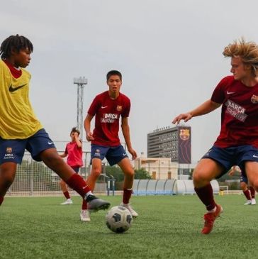 Young soccer players in action on a field, wearing Barça uniforms.