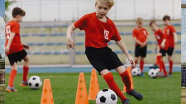 Young soccer players practicing dribbling skills with cones on the field.