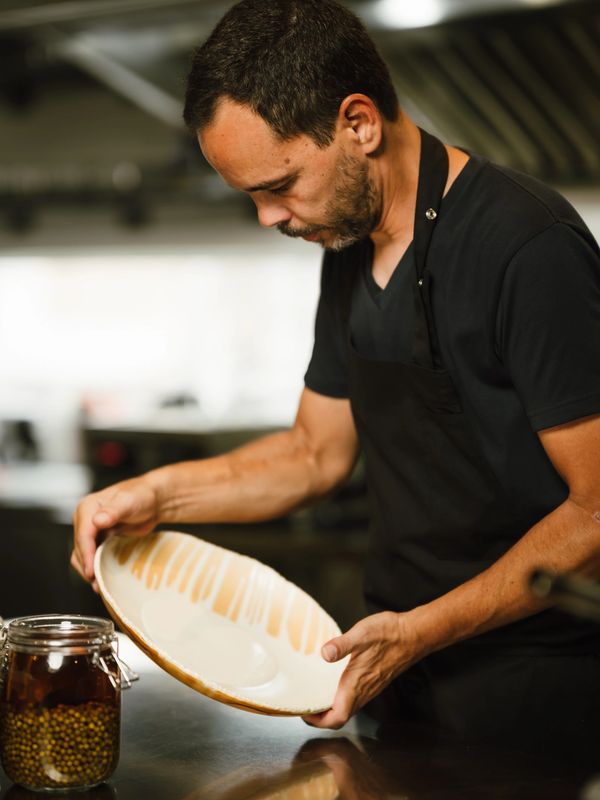 Chef inspecting a ceramic plate in a kitchen.