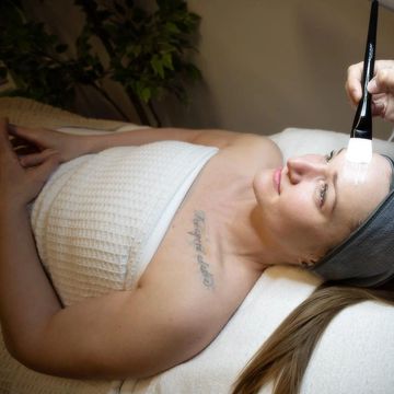 Woman receiving a facial treatment with a brush at a spa.